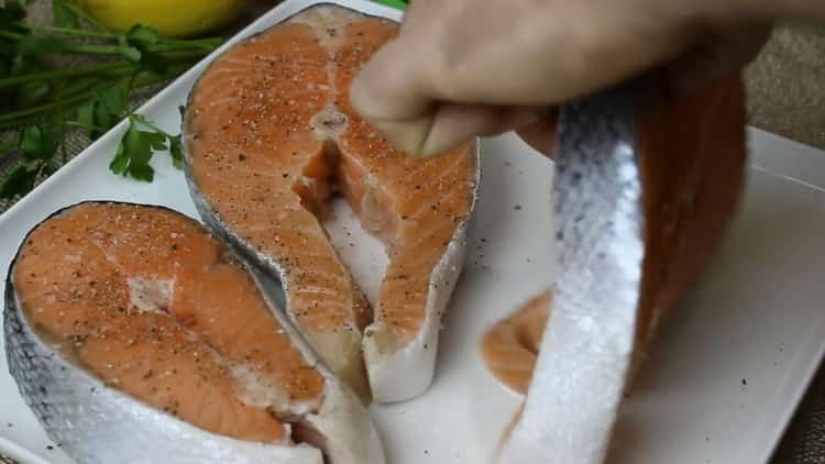Um Lachssteak in einer Pfanne zu kochen, pfeffern und salzen Sie den Fisch