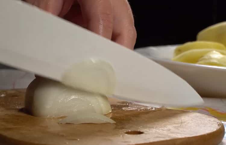 Um Kabeljau mit Kartoffeln im Ofen zuzubereiten, hacken Sie die Zwiebel