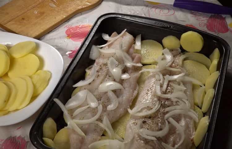 Um Kabeljau mit Kartoffeln im Ofen zuzubereiten, legen Sie die Zwiebeln auf den Fisch