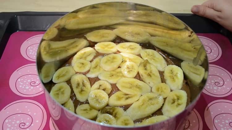 Um einen Schokoladen-Bananen-Kuchen zuzubereiten, legen Sie die Banane auf den Teig