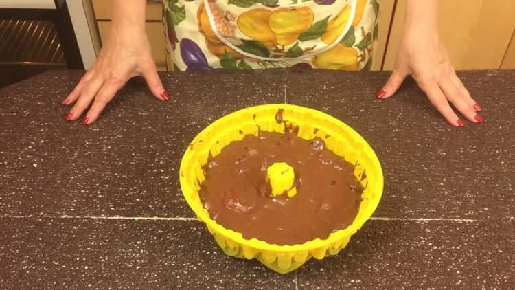 Um ein Schokoladenmuffin mit einer Kirsche zuzubereiten, füllen Sie den Teig in eine Form