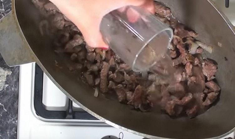Aggiungi acqua alla carne e alla cipolla e lascia in umido sotto il coperchio.
