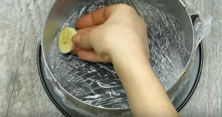 Legen Sie die Bananenscheiben in einer einzigen Schicht in einer abnehmbaren Form mit Frischhaltefolie.