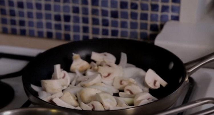 Friggere la cipolla con i funghi in una padella.