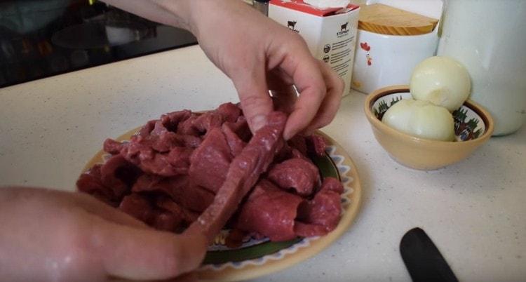 Das Rindfleisch in lange Scheiben schneiden.