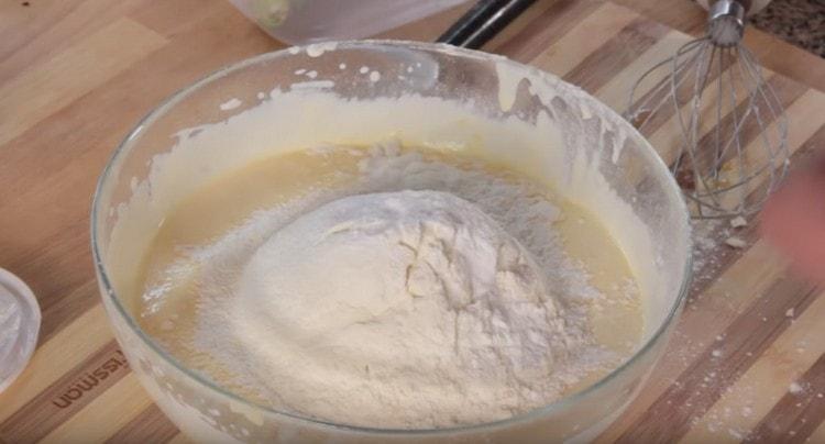 Magdagdag ng kulay-gatas sa masa ng itlog, pati na rin ang harina at baking powder.