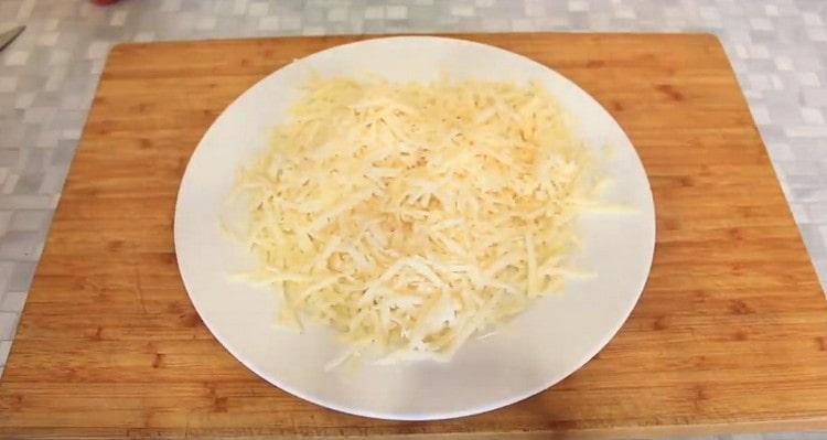 Käse auf einer groben Reibe reiben.