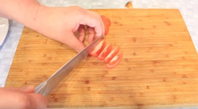 Wir schneiden die Tomaten in Scheiben.