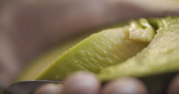 Rimuovi la pietra dall'avocado tagliata a metà e seleziona la polpa con un cucchiaio.