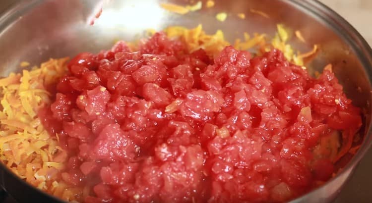 Aggiungi i pomodori in scatola tritati a metà della massa vegetale.