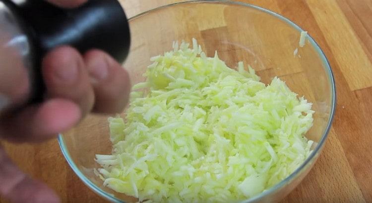 Strofina le zucchine su una grattugia, sale.