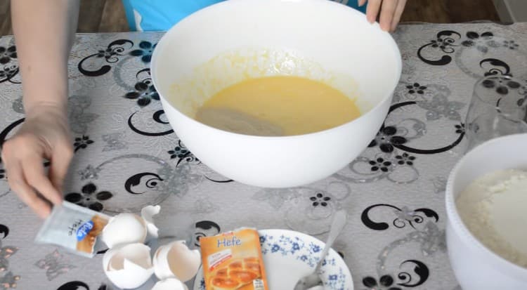 Fügen Sie dann Eier zum Teig hinzu und gießen Sie Trockenhefe hinein.