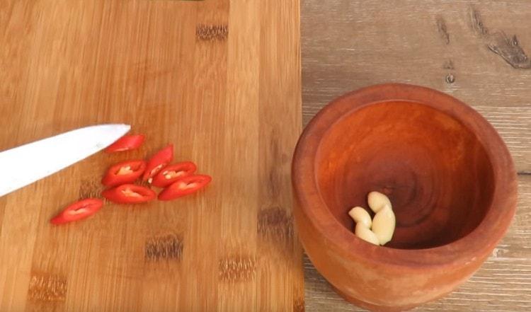 Chili papričky nakrájejte na kroužky a přidejte do česneku.
