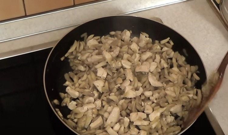 Fügen Sie den Pilzen mit Zwiebeln Hühnchen hinzu.