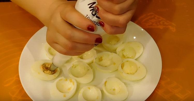 Χρησιμοποιώντας μια σακούλα ζαχαροπλαστικής, γεμίζουμε τα λευκά αυγών με τη μαγειρεμένη μάζα.