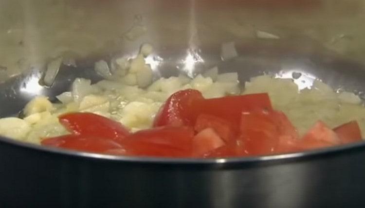 Į svogūną įpilkite supjaustytų pomidorų.