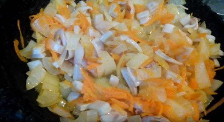 Friggere le cipolle con le carote e le fette di calamaro in una padella.