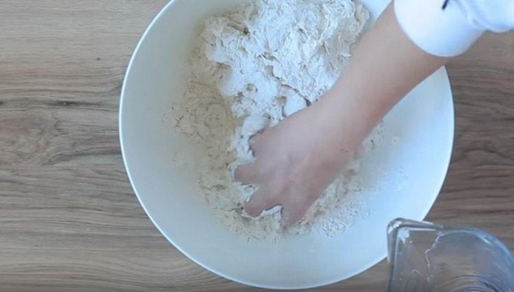 Fügen Sie dem Mehl Wasser hinzu und kneten Sie den Teig.