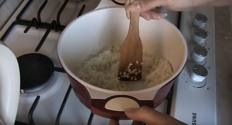 Сложете ориз в тиган и запържете няколко минути.