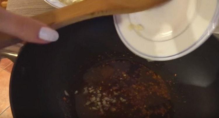 Versare l'aglio schiacciato nell'olio.