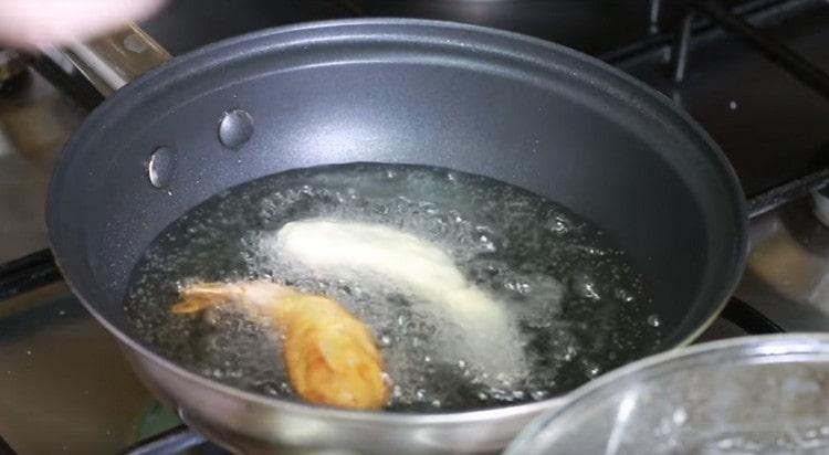 Distribuire i gamberi in olio bollente e friggere su entrambi i lati fino a quando diventano dorati.