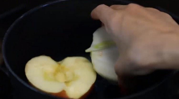 V stewpan rozprostřel půl jablka a půl cibule.