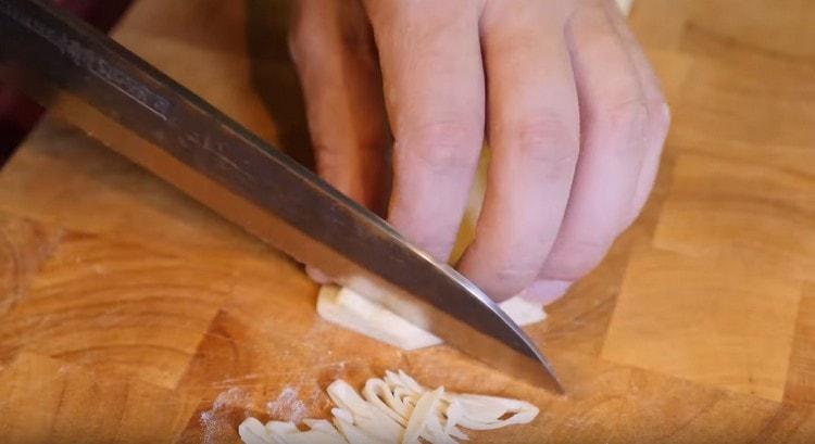 Tagliare il rotolo risultante dall'impasto della pasta.