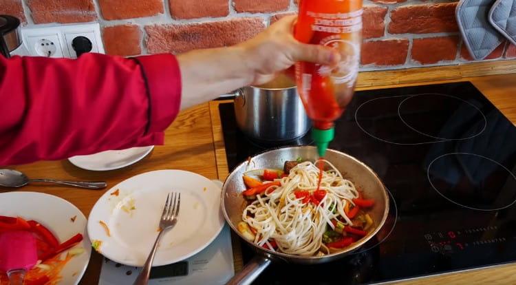 Metti i noodles nella padella, aggiungi la salsa di soia e la salsa sriracha.