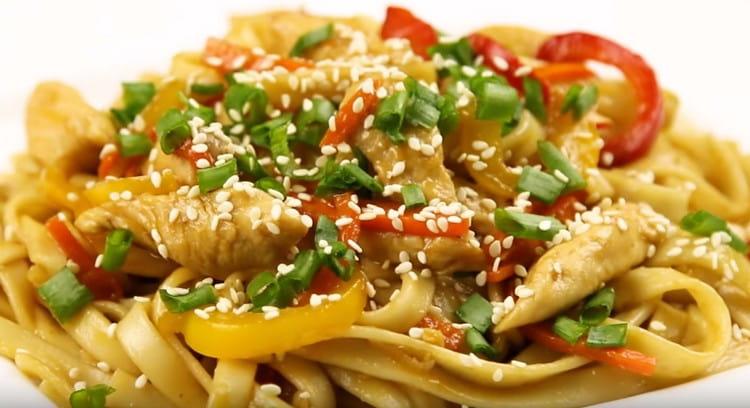 Gli spaghetti wok con pollo saranno più efficaci se serviti se cosparsi di verdure e semi di sesamo.
