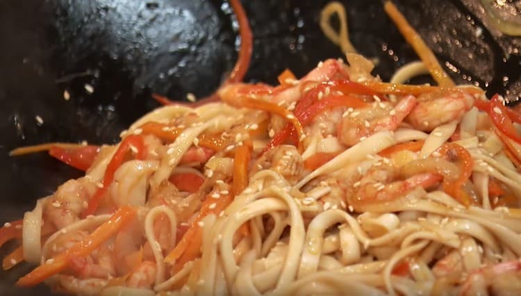 Quindi aggiungere gli spaghetti, mescolare, condire il piatto con salsa di soia, cospargere con semi di sesamo.