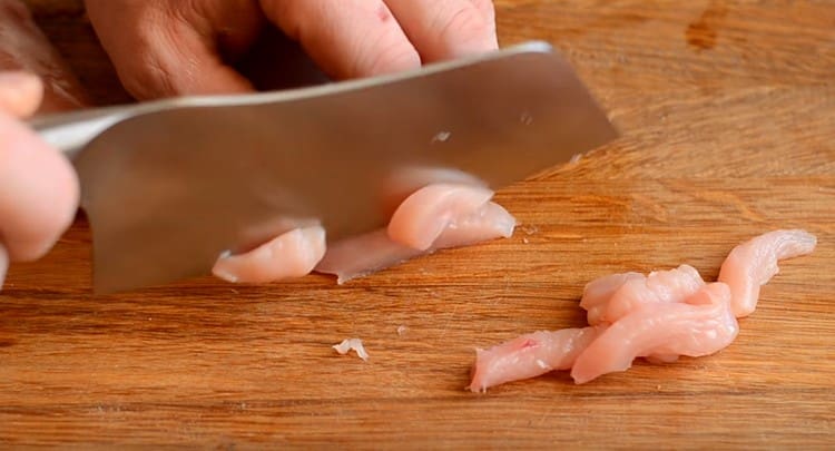 Tagliamo il pollo a fette lunghe e sottili.