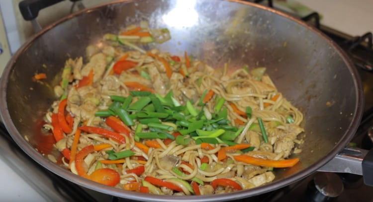 Ανακατέψτε udon με κοτόπουλο και λαχανικά, προσθέστε πράσινα κρεμμύδια.