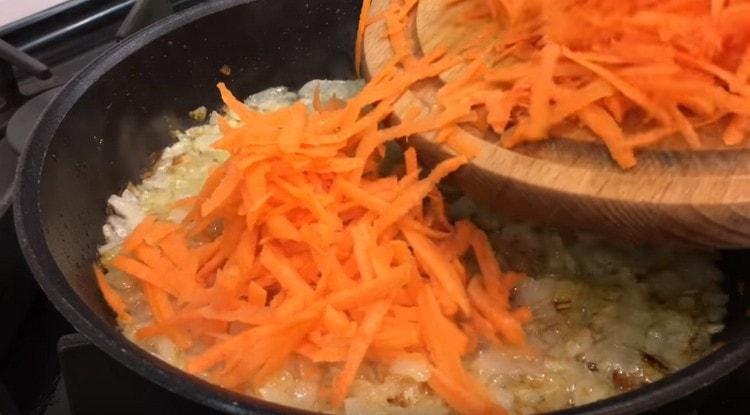 Die geriebenen Karotten zu den Zwiebeln in der Pfanne geben.