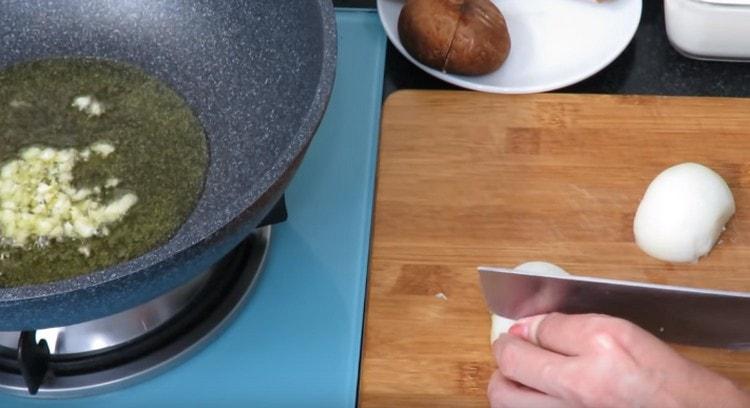 Ενώ το σκόρδο τηγανίζεται σε λάδι, ψιλοκόψτε το κρεμμύδι.