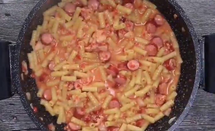 Gumalaw ng pasta na may sarsa at sausages.