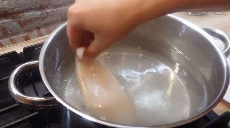 Wir kochen Wasser in einem Topf, salzen es und verteilen den Tintenfisch.