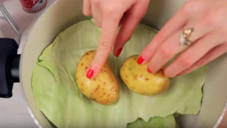 Покриваме зелевите рулца с друго листо зеле, отгоре можете да поставите картофи.