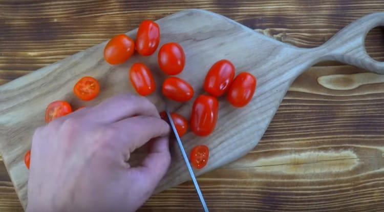 Нарежете чери доматите на две половини.