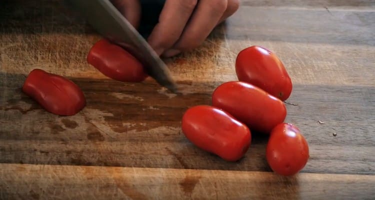 Vyšninius pomidorus supjaustykite ketvirčiais.