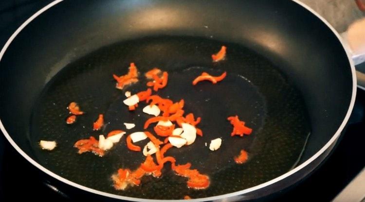 Do pánve vložte chilli papričky a česnek.