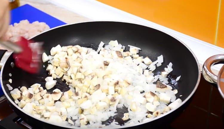Τρίψτε τα κρεμμύδια και τα μανιτάρια σε ένα τηγάνι.
