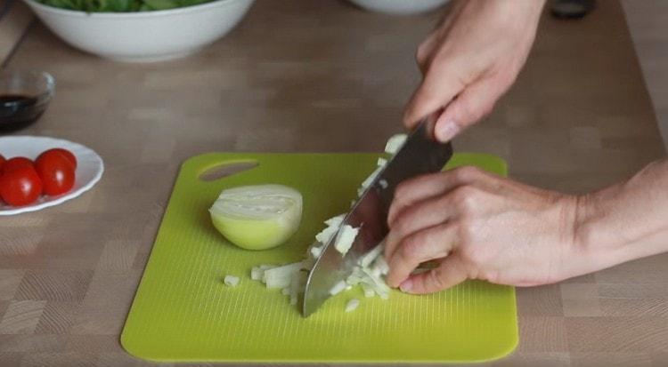 Macinare la cipolla sul tagliere.