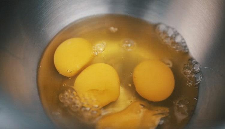 Избиваме яйцата в купата с тестото.