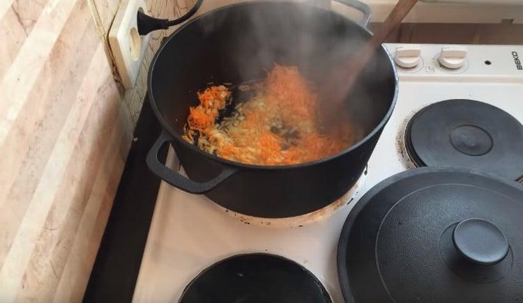 Fügen Sie Karotten der Zwiebel hinzu und kochen Sie das Gemüse bis weich.