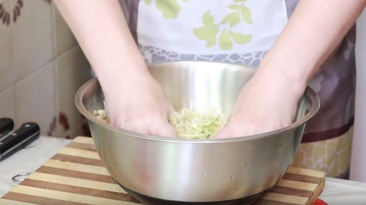 Χέρια συνθλίβονται λάχανο, προσθέτοντας λίγο αλάτι.