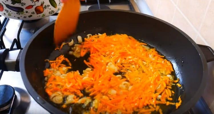 Friggere la cipolla con le carote in olio vegetale.