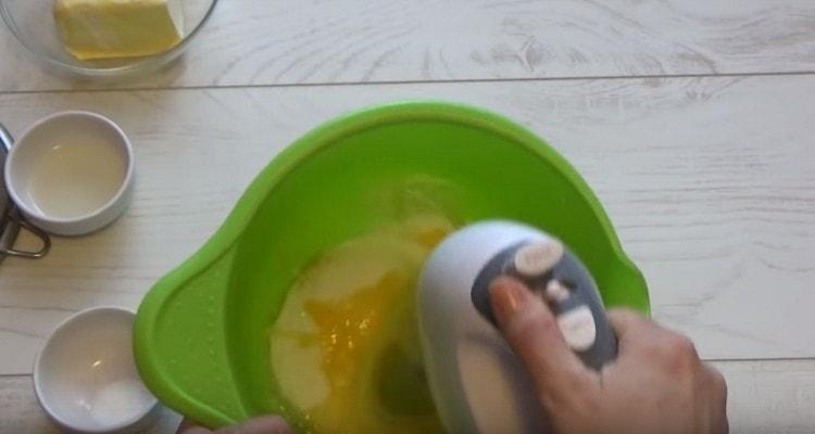 Χτυπήστε τα αυγά με ζάχαρη χρησιμοποιώντας ένα μίξερ.