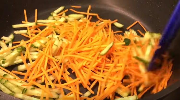 Добавете краставицата, нарязана на ивици, към морковите и запържете зеленчуците заедно
