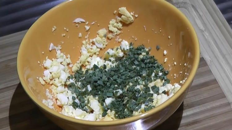 Сваряваме сварените яйца, смесваме с нарязания зелен лук.
