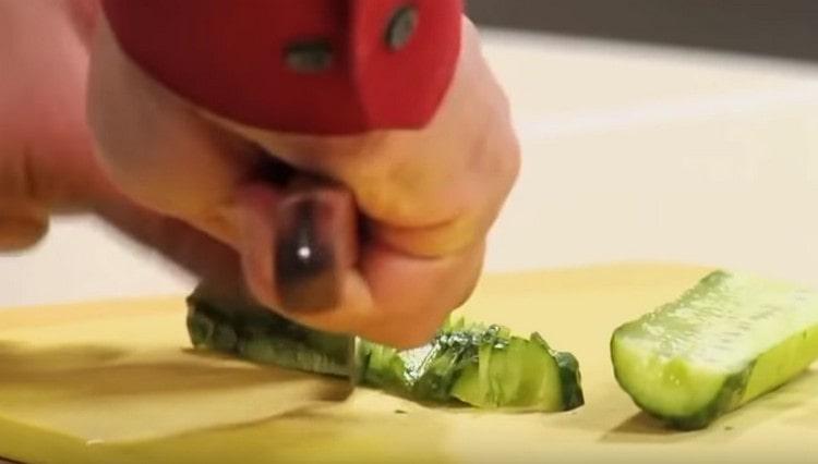 Нарежете обелената краставица на полукръгове.